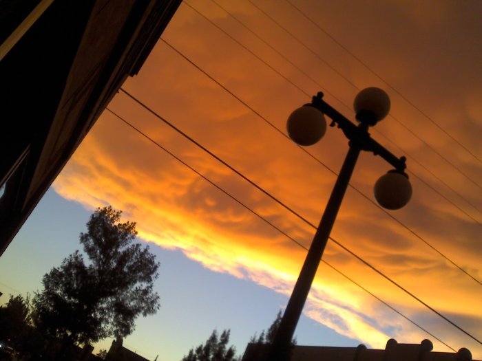 A photo of a lamp post silhouetted by clouds, at an odd angle.
