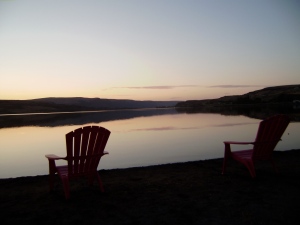 two empty chairs lakeside at sunset